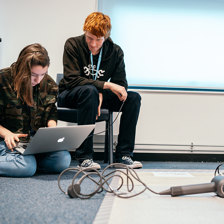 Two sixth form students programming a robot to navigate around a Dyson Supersonic in a James Dyson Foundation robotics workshop.