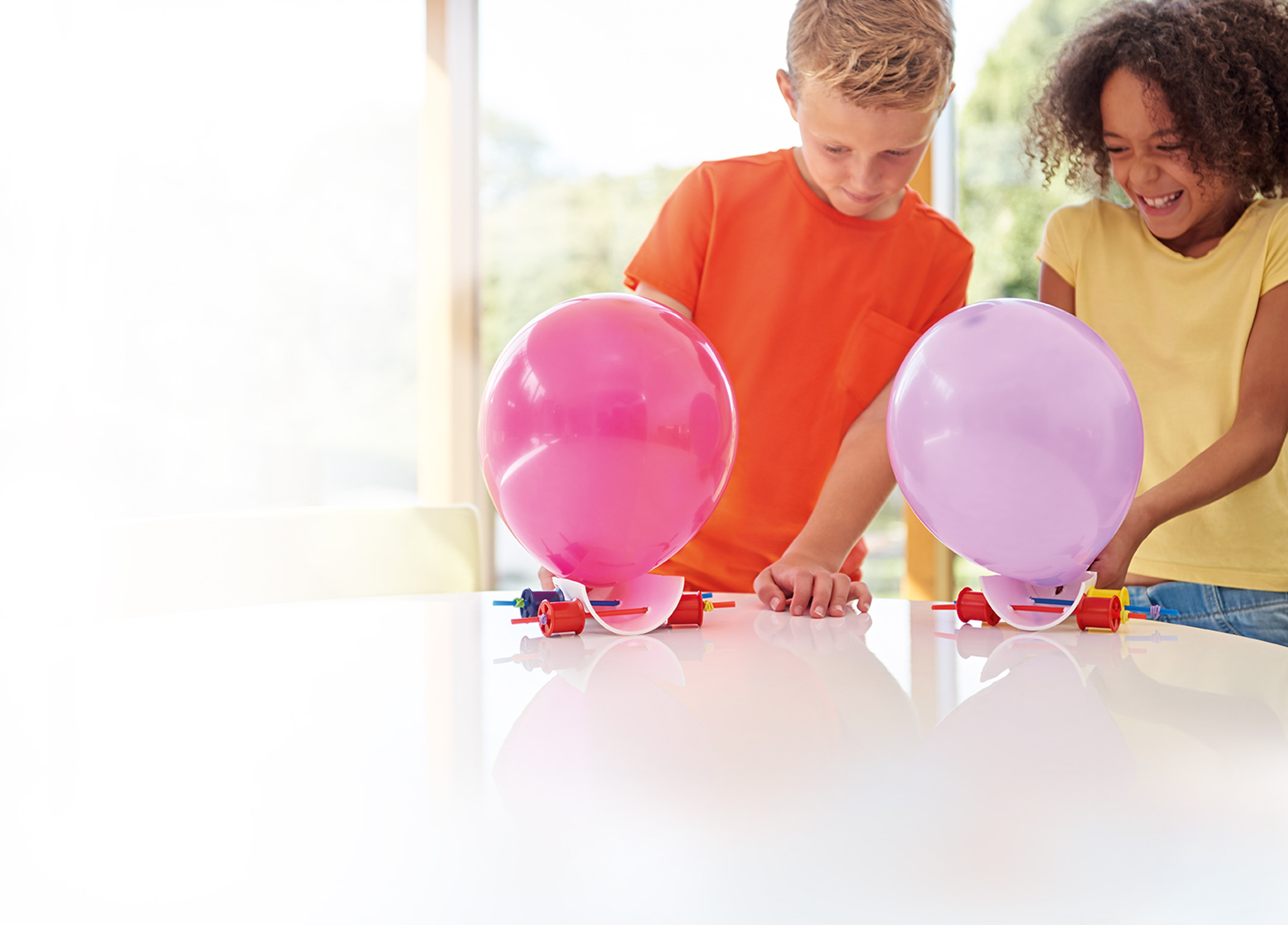 Two children racing the balloon cars they have made from a James Dyson Foundation challenge card. 