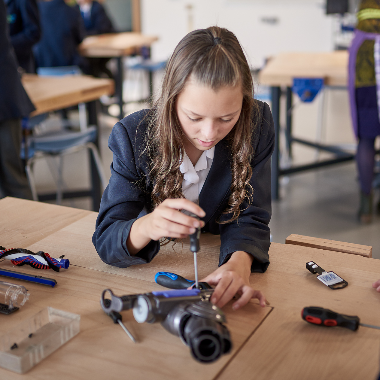 Female school student using a screwdriver to take apart a Dyson vacuum cleaner head - an activity from the James Dyson Foundation Engineering Box.