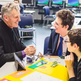 Two students and their teacher working on electronics.
