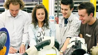 Four engineers working together to improve a prototype.