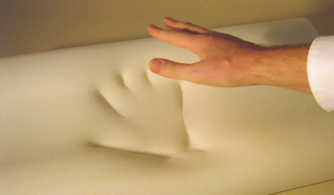 A close-up of a hand on a memory foam mattress.