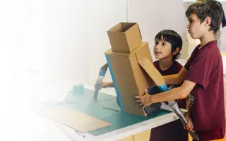 Two students building a prototype from cardboard and excess Dyson machine parts.