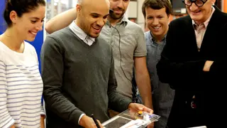 Four students and Sir James Dyson looking at a student's project.