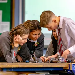 Four students working together to disassemble vacuum cleaner machine heads.