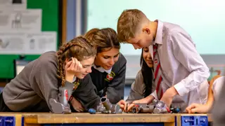 Four students working together to disassemble vacuum cleaner machine heads.