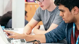 Two students programming Lego Mindstorms robots.