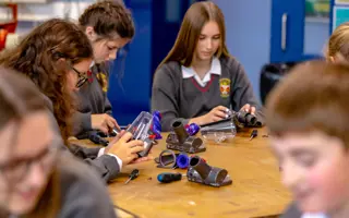 A group of students disassembling a Dyson vacuum cleaner machine head.